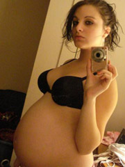 Pregnant girl poses in high heels and miniskirt.