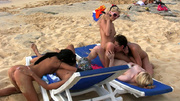 Playful naked teens licking and toying on the beach while being watched by passerbys.