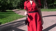 Smily young erotic nymph in sexy red dress walking in the park and exposing her perfect legs.