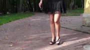 High heeled teen hottie in black miniskirt showing her sexy legs while walking in the park.